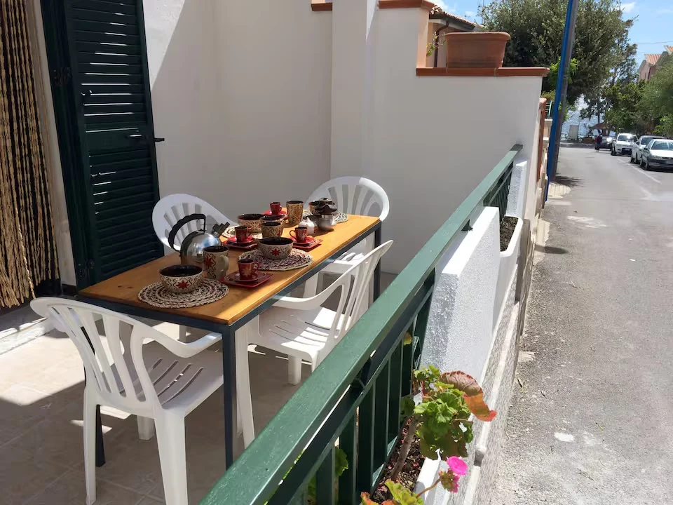 Terraza de Conchiglie 8 preparada para desayunar, con barandilla verde y persianas abiertas